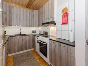 A kitchen with wooden cabinets, a microwave, a toaster, and an oven. - Hatun huilaus by Interhome (Ilomantsi)