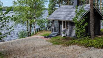A cabin with a gravel driveway, a wooden deck, and a view of a lake.