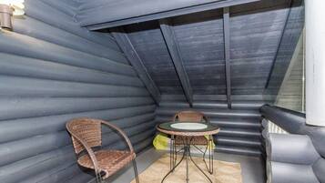 A compact, enclosed space with a curved ceiling, a small round table, two wicker chairs, and a light fixture.
