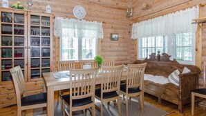 A wooden cabin interior with a dining table, chairs, a sofa, a cabinet with glass doors, and a clock on the wall. - Hatun huilaus by Interhome (Ilomantsi)