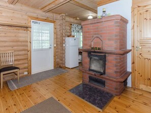 A wooden interior with a brick fireplace, a white refrigerator, and a bench. - Hatun huilaus by Interhome (Ilomantsi)