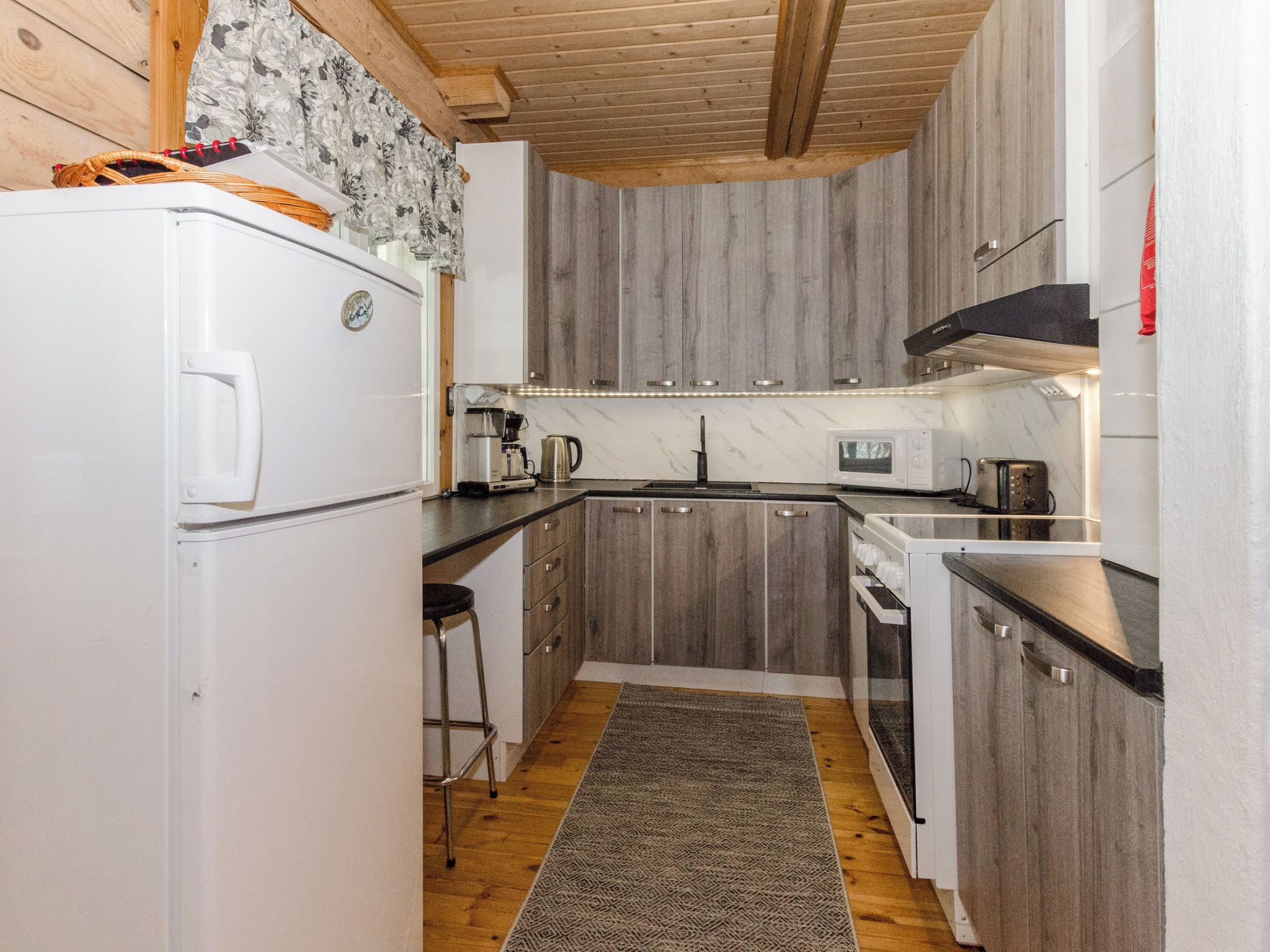 A compact kitchen with a refrigerator, coffee maker, microwave, and a sink.