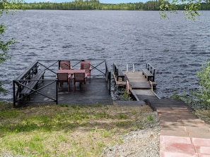 Une jetée en bois s’avançant dans un lac, avec un espace aménagé pour s’asseoir et un petit pont.