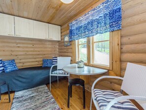 A cozy cabin interior with a wooden interior, a round table, a sofa, and a window with a view of the outdoors.