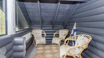 A covered outdoor seating area with cushioned chairs and a woven rug.
