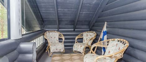 Een overdekt terras met comfortabele fauteuils en een geweven vloerkleed.