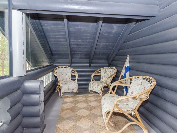 A covered outdoor seating area with cushioned chairs and a woven rug.