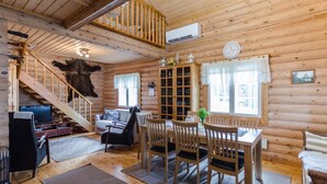 A log cabin interior with a dining area, a sofa, a TV, and a staircase. - Hatun huilaus by Interhome (Ilomantsi)