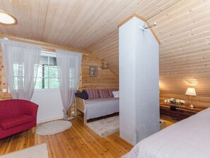 Une chambre confortable dans un chalet, avec un lit, une chaise, un bureau et une fenêtre avec des rideaux.