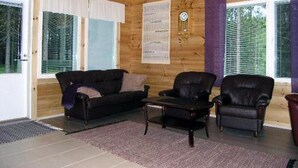 A cozy room with a wooden ceiling, a black leather sofa, two leather armchairs, and a small table. - Kärkelä by Interhome (Kiuruvesi)