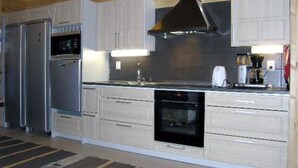A modern kitchen with white cabinetry, a stainless steel refrigerator, a built-in oven, and a coffee maker. - Kärkelä by Interhome (Kiuruvesi)