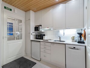 A compact kitchen with white cabinets, a microwave, a coffee maker, and a dishwasher.