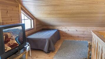 A small, wooden room with a bed, a television, and a window.