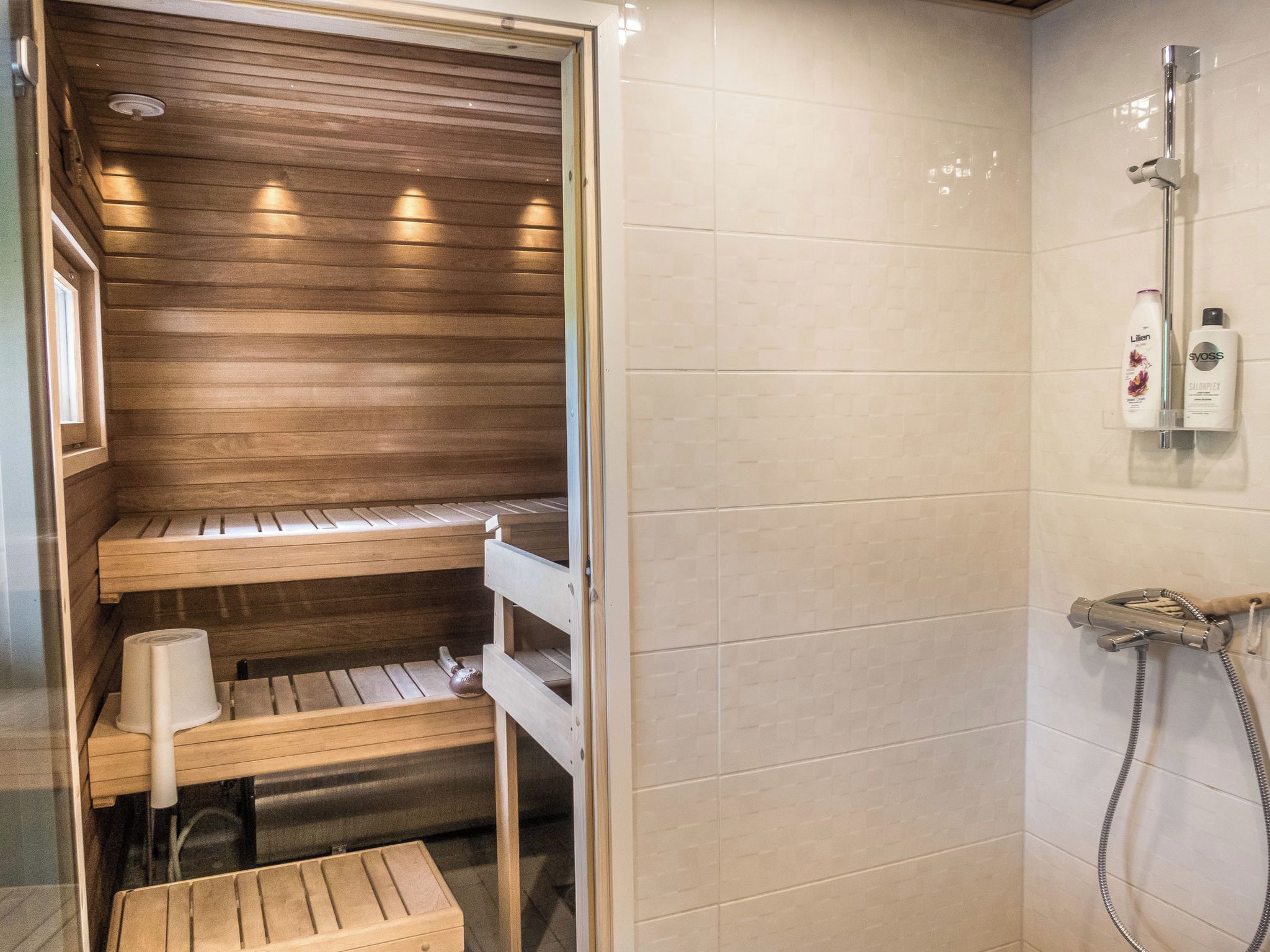 A sauna with wooden benches and a shower area with a handheld showerhead.