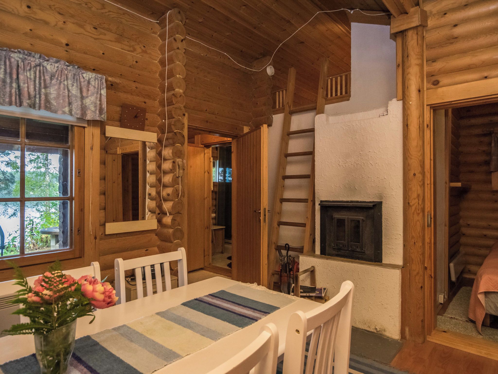 L’intérieur d’une cabane en rondins, avec une table à manger, des chaises, une cheminée et un escalier.