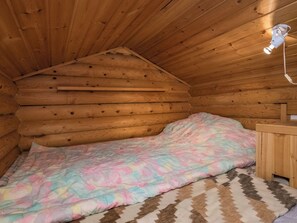 Une chambre de style rustique, avec un lit, une table de chevet en bois et un luminaire fixé au plafond.