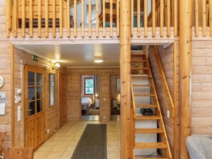 Ein Holzinnenraum mit einer Treppe zu einem Schlafzimmer auf dem Dachboden, einem sichtbaren Bett und einer Tür mit einem Schild.