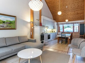 A modern living room with a sofa, a round coffee table, and a dining area with chairs and a table. - Vacation home Reppu by Interhome (Sotkamo)