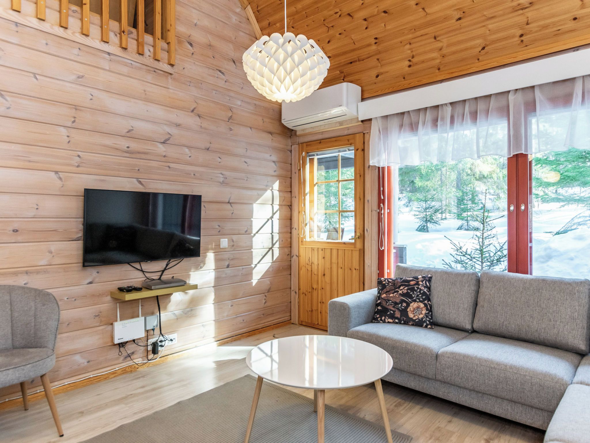 A modern log cabin interior with a television, sofa, and a round table.