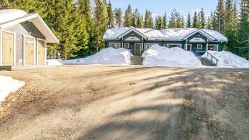 A two-story lodge with a dirt driveway leading to a set of stairs.