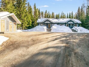 A two-story lodge with a dirt driveway leading to a set of stairs.