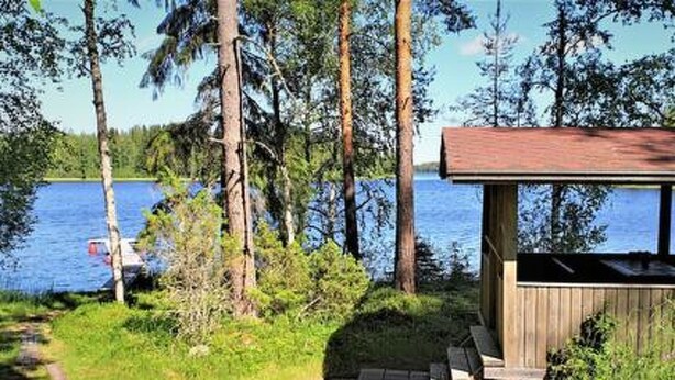 Puinen mökki, jossa on terassi ja josta avautuu näkymä järvelle.
