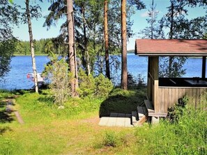 Una cabaña de madera con terraza, con vista a un lago.