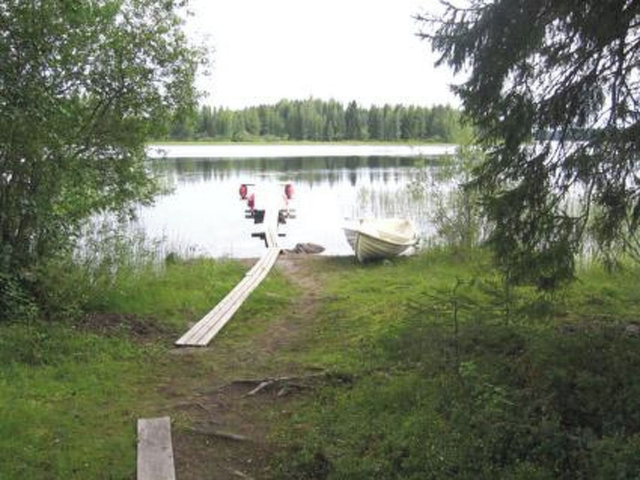 Un muelle se adentra en un lago tranquilo rodeado de árboles.