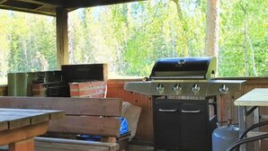 Ulkoterassi, jossa on grilli, pöytä ja penkki.
