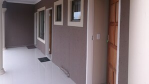 A hallway with a tiled floor, a door with a wooden frame, and a window with a view of the outside. - M n M Guest House in Polokwane Turfloop (Polokwane)