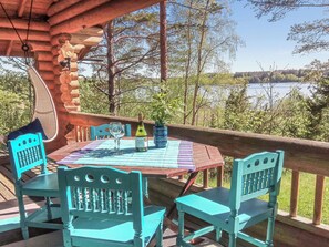 Puisesta laudasta rakennettu terassi, jossa on pöytä ja tuoleja, ja josta avautuu näkymä järvelle.