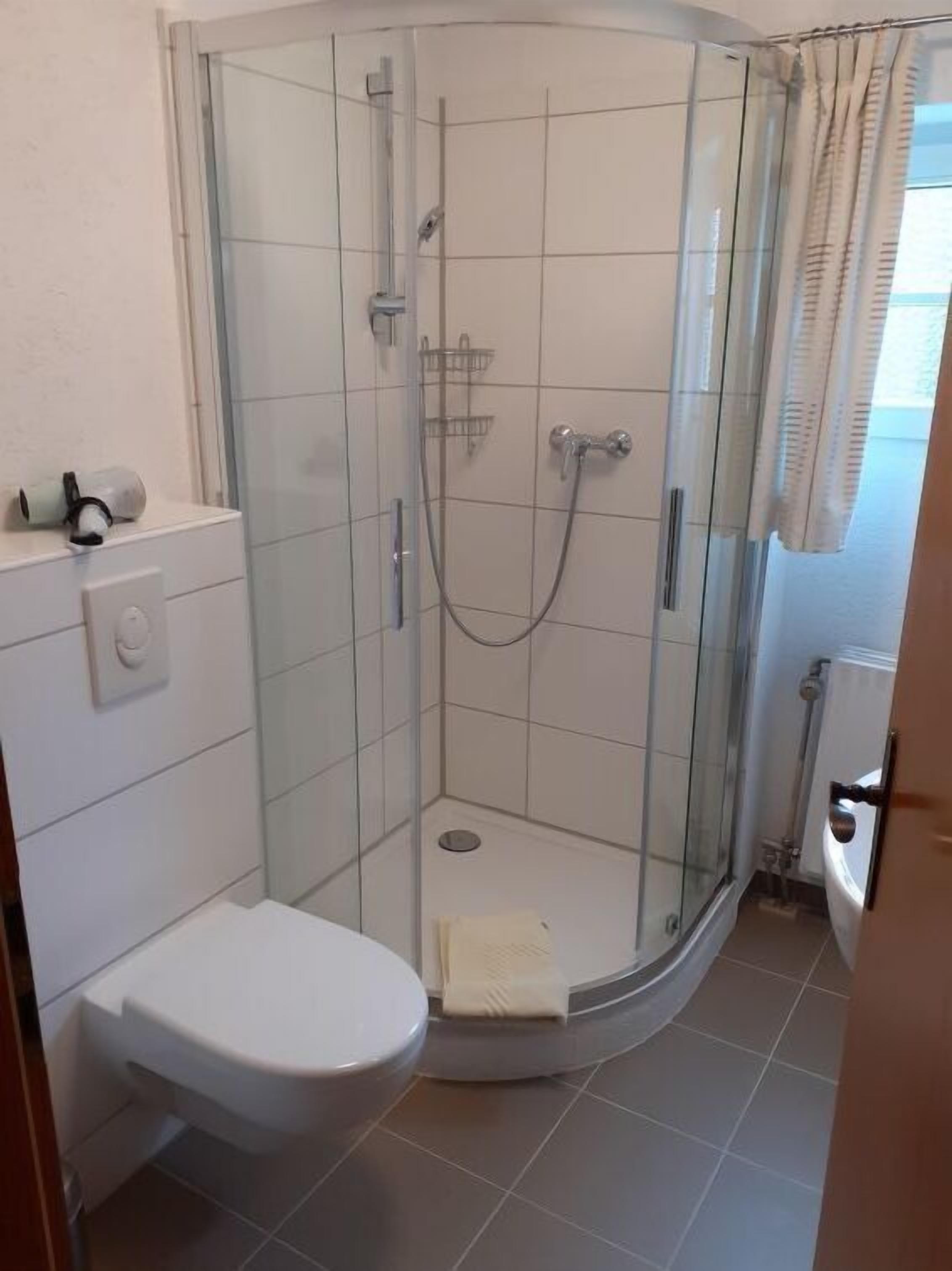Une petite salle de bain moderne avec une douche à parois de verre, des toilettes blanches et un porte-serviettes.