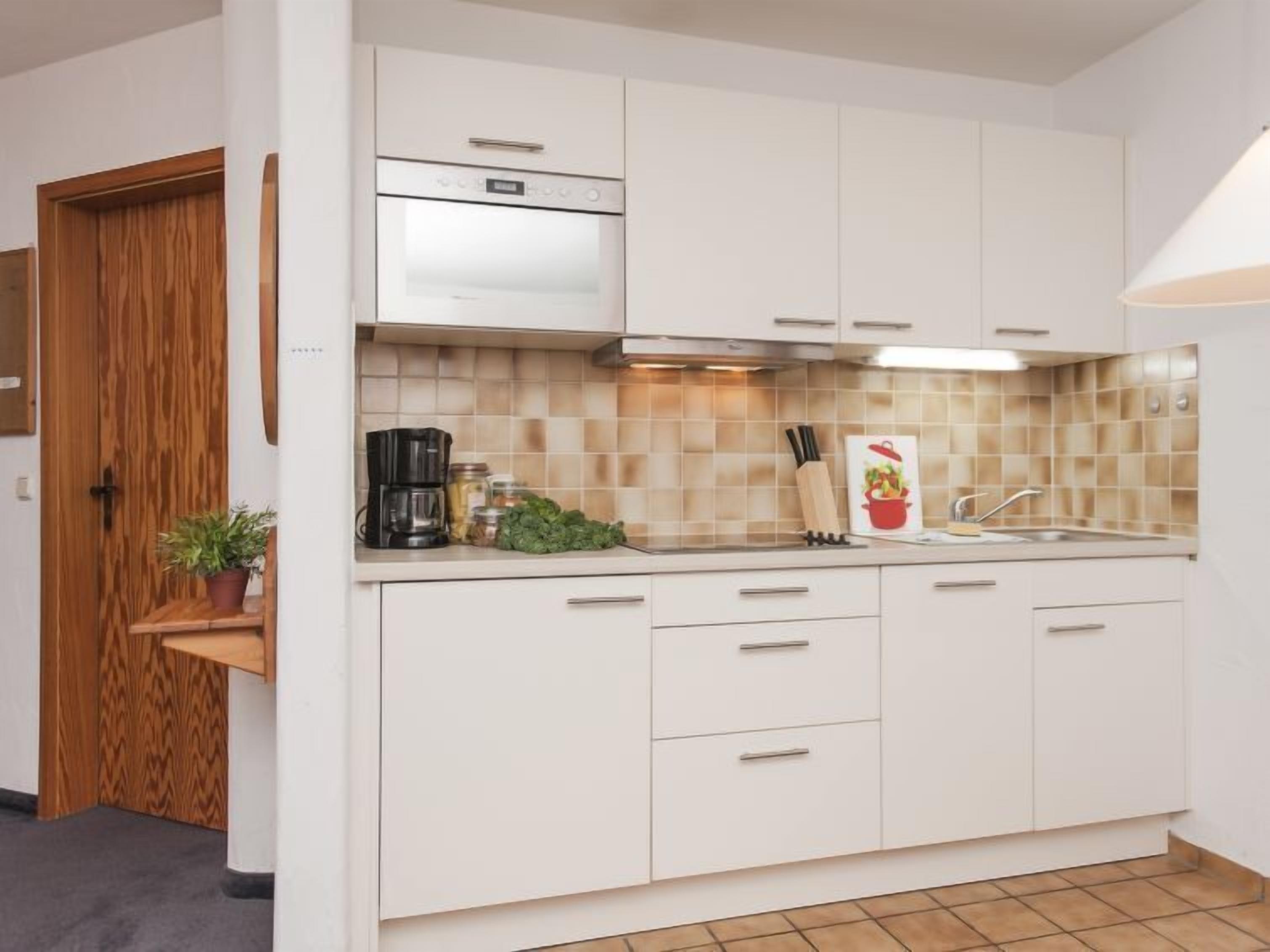 A modern kitchen with white cabinets, a stainless steel oven, and a tiled backsplash.
