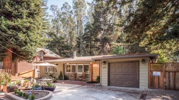 Einbungalow mit Garage, umgeben von bewaldetem Gelände.
