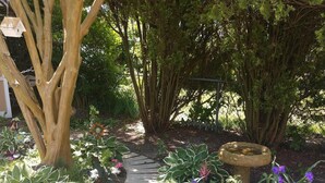 A garden with a wooden bench, a birdhouse, and various plants. - NEW LISTING! - Quaint Cape May Beach House Only Blocks to the Beach (North Cape May)
