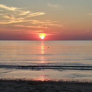 A beach at sunset with calm waters reflecting the sky.