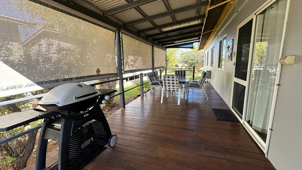 Une terrasse extérieure couverte, équipée d’un barbecue, de chaises et d’une table.