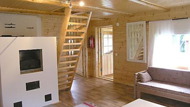 Un interior de madera con una escalera, un sofá y una chimenea.