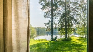 A window view of a lake with trees and a grassy area. - Saniainen 5 by Interhome (Pielavesi)