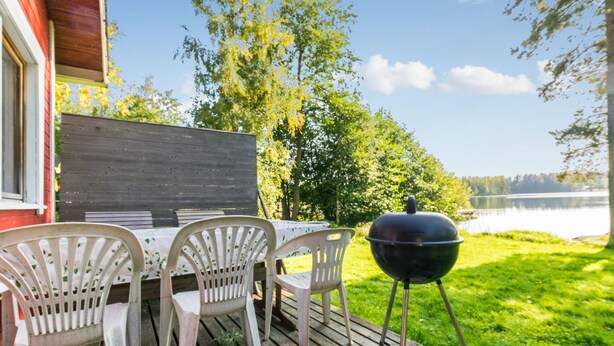 A wooden deck with outdoor furniture and a grill, overlooking a lake. - Saniainen 5 by Interhome (Pielavesi)