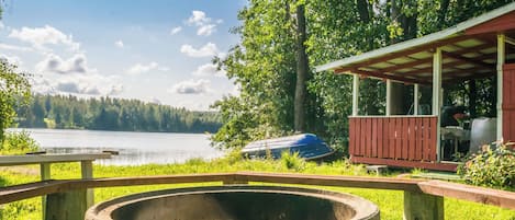A lakeside view with a wooden deck, a barbecue grill, and a covered seating area.