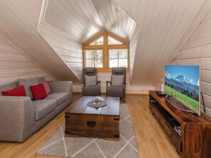 Ein Loft-Zimmer mit Holzboden, einer Couch, zwei Sesseln, einem Couchtisch und einem Fernseher auf einem Holzboden.