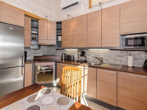 A modern kitchen with stainless steel appliances, wooden cabinets, and a stone backsplash.