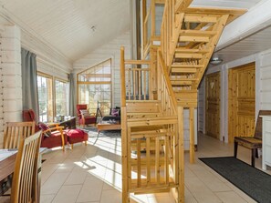 Ein geräumiger Wohnbereich mit einer Holztreppe, großen Fenstern und einer gemütlichen Sitzecke.