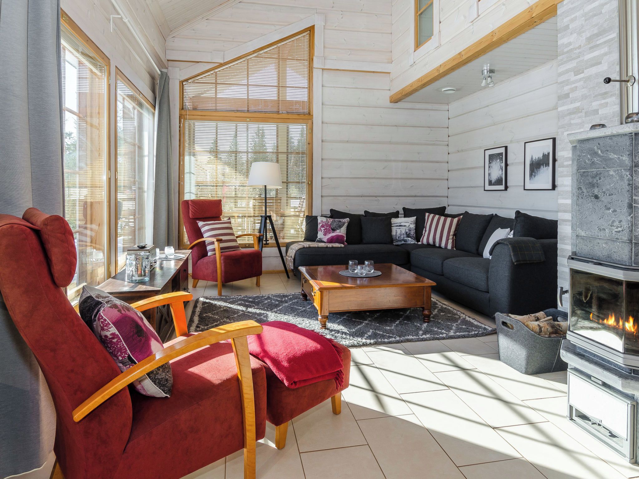 Un salon moderne avec une cheminée, un canapé rouge, un canapé noir et une table basse en bois.