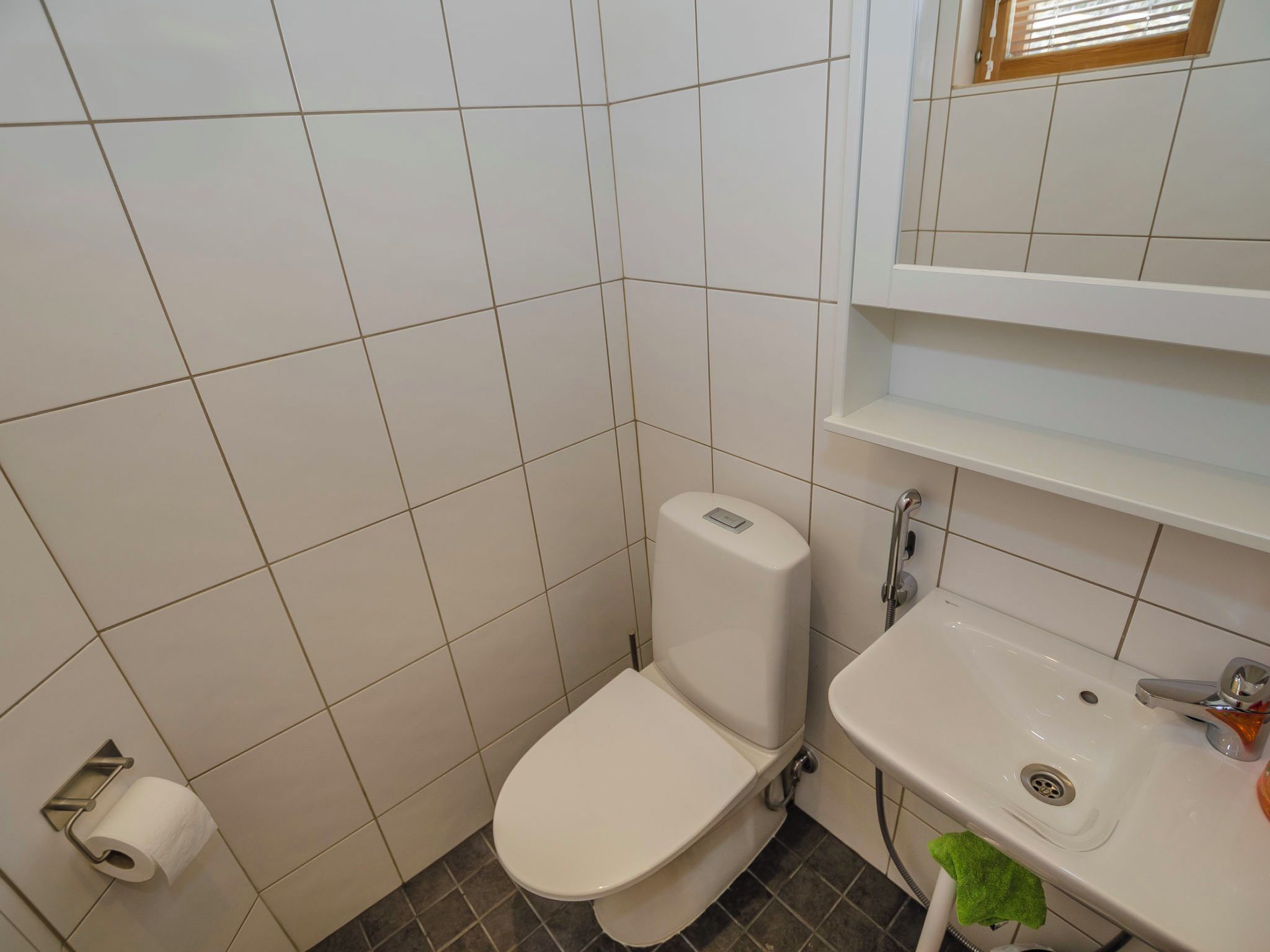 Une petite salle de bain avec des toilettes, un lavabo et un miroir au-dessus du lavabo.