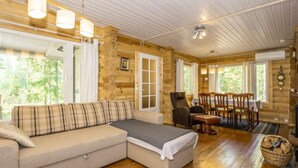 Un intérieur chaleureux de chalet en bois, avec un canapé d’angle, une table à manger et des chaises.