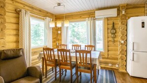 L’intérieur chaleureux d’un chalet comprend une table à manger, des chaises, un canapé et un réfrigérateur.