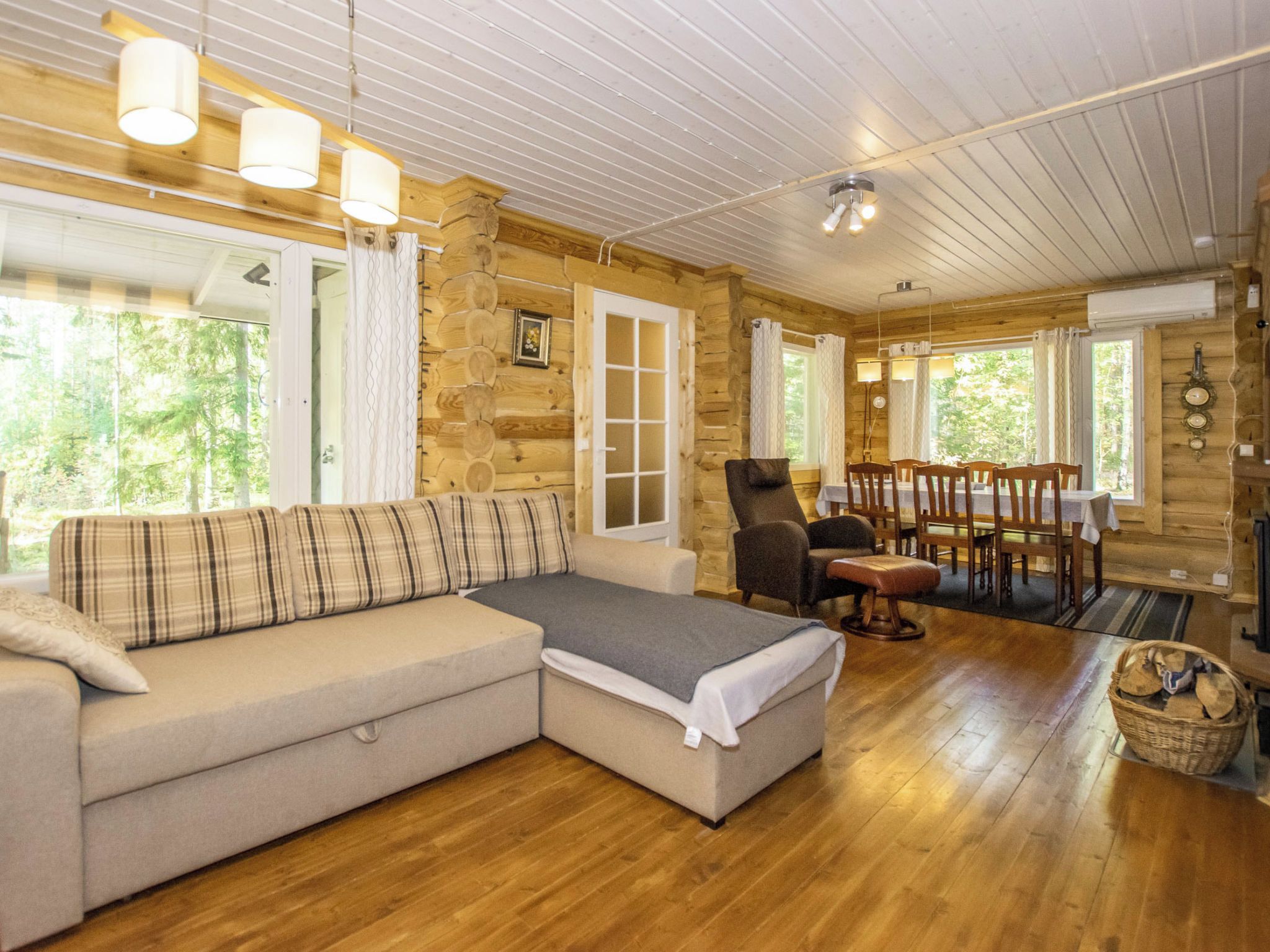 L’intérieur d’un chalet confortable, avec une cheminée, un canapé d’angle et une table à manger entourée de chaises.