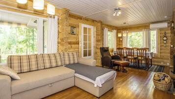 L’intérieur d’un chalet confortable, avec une cheminée, un canapé d’angle et une table à manger entourée de chaises.